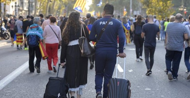 Dos turistas con sus maletas por una calle de Barcelona en la que marcha una manifestación independentista. AFP/Josep Lago