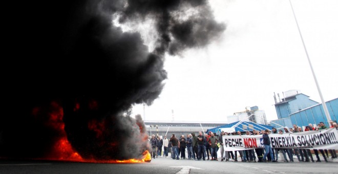 Trabajadores de la planta Alcoa de A Coruña, durante la concentración que llevan a cabo a las puertas de la fábrica, donde han quemado neumáticos y cortado el tráfico, en protesta y en lucha contra el cierre de la aluminera, que supondría el despido colec