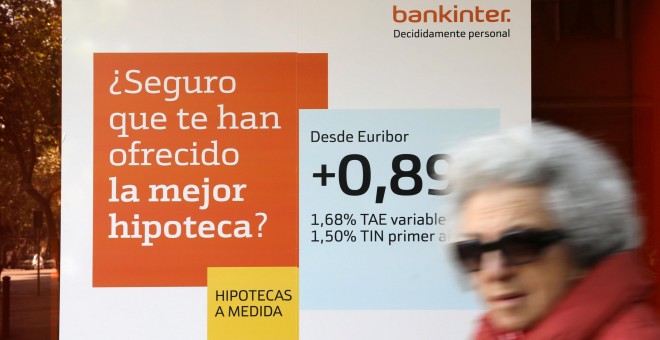 Una mujer pasa junto a una publicidad de hipotecas en una sucursal de Bankinter. REUTERS/Susana Vera