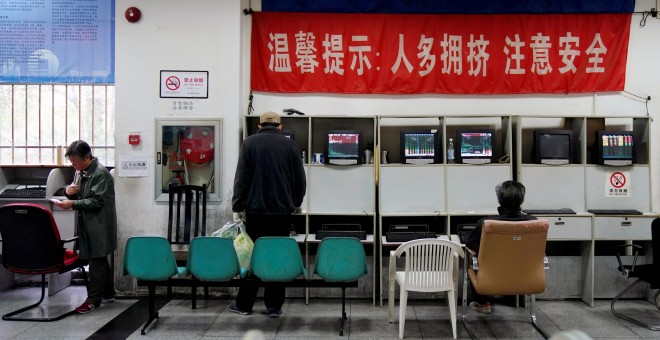 Los inversores miran los monitores que muestran información sobre acciones en una firma de brokers en Shanghai (China). REUTERS / Aly Song