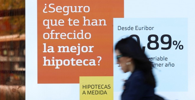 Una mujer pasa junto a una publicidad de hipotecas en una sucursal de Bankinter. REUTERS/Susana Vera