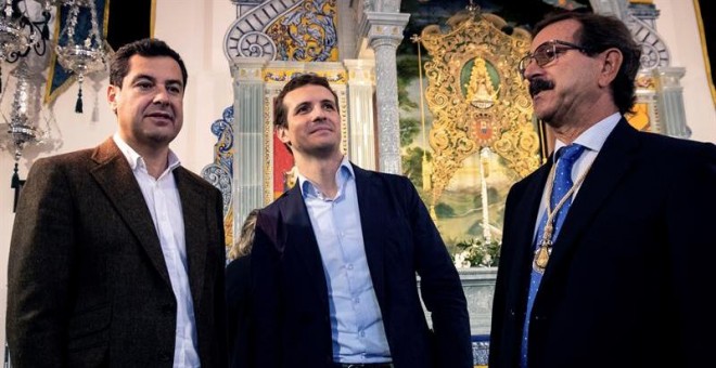 El presidente del PP, Pablo Casado (c), acompañado del presidente del PP-A, Juanma Moreno (i), y del presidente de la Hermandad del Rocío de Huelva, Antonio Sánchez de Piña. /EFE