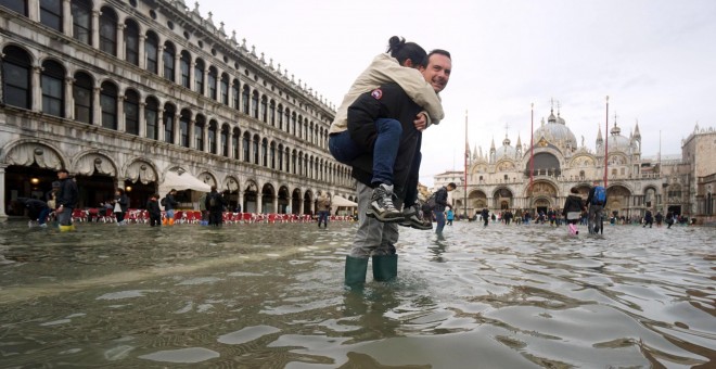 Un hombre carga a sus espaldas con su hija en la Plaza de San Marco de Venecia, inundada como consecuencia del temporal de lluvias. Andrea Merola/EFE