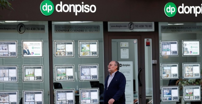 Un hombre pasa por delante de una oficina de una inmobiliaria en Barcelona. REUTERS/Albert Gea
