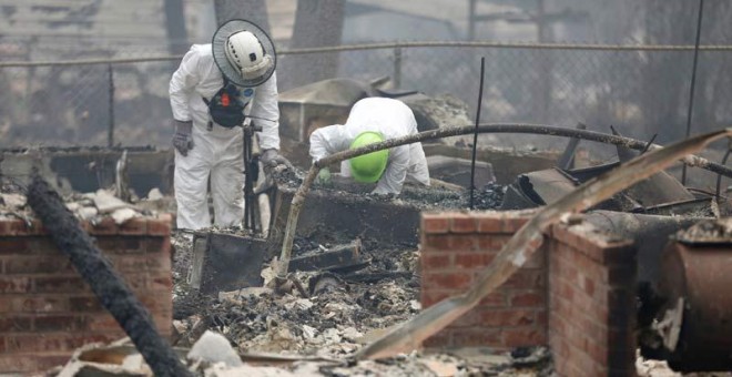 Miembros de un equipo de rescate buscan restos humanos en una de las miles de casas quemadas en California. (TERRAY SILVESTER)