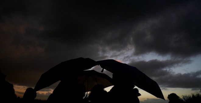 Un grupo de personas se refugia de la lluvia con sus paraguas en el parque madrileño del Templo de Debod. REUTERS/Sergio Perez