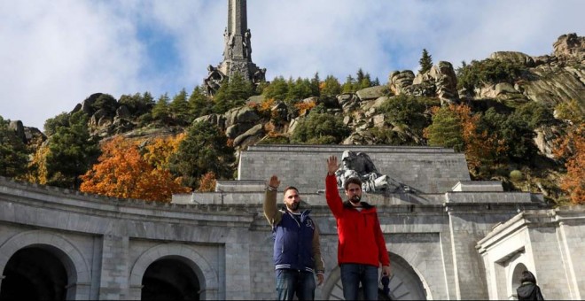Dos jóvenes realizan el saludo fascista delante de la entrada principal del Valle de los Caídos. (SUSANA  VERA | REUTERS)
