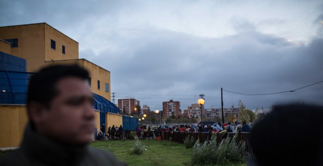 Cientos de solicitantes de asilo esperan la cola durante toda la noche para obtener un cita previa con la que comenzar sus trámites, en la comisaría de Extranjería de Aluche, Madrid. JAIRO VARGAS