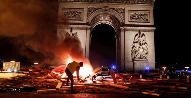 Un manifestantes de los llamados 'chalecos amarillos' prende fuego a una barrica frente al Arco del Triunfo de París en la manifestación contra el alza de precio de los carburantes.- REUTERS/Benoit Tessier