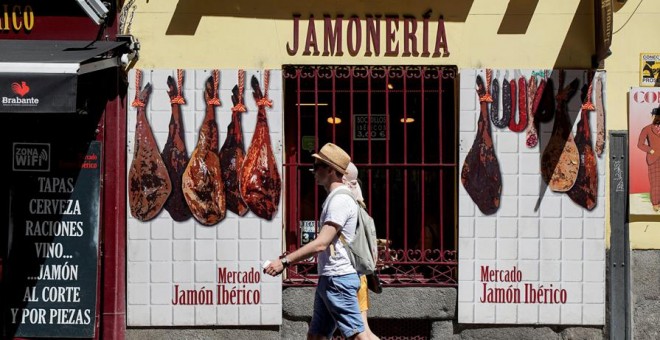 Una pareja de turistas pasa por delante de una jamonería en el centro de Madrid. REUTERS/Paul Hanna
