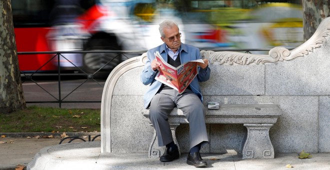 Un pensionista lee el periodico en un banco en el centro de Madrid. REUTERS/Paul Hanna