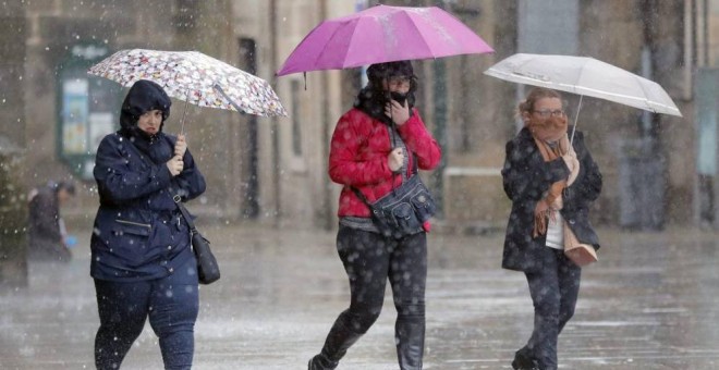 Imagen de archivo de varias personas transitan bajo la lluvia la plaza del Obradoiro, en Santiago de Compostela/EFE