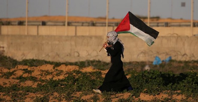 Una mujer con la bandera palestina en una protesta contra Israel en la frontera con Gaza. REUTERS/Ibraheem Abu Mustafa