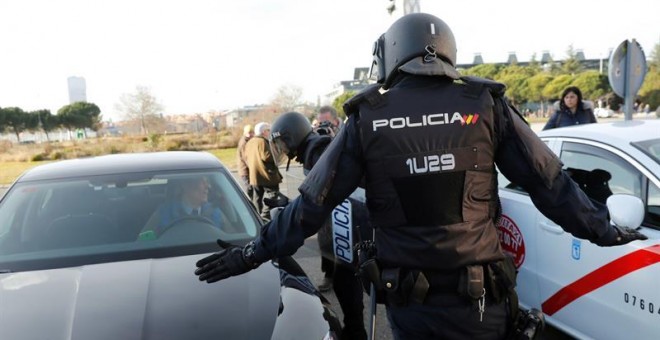 Efectivos de la Policía Nacional entre un vehículo de licencia VTC y un taxi a las puertas del recinto ferial de Ifema. EFE/Chema Moya