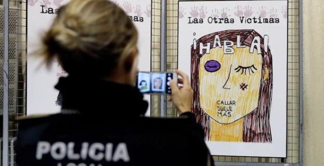 Una agente de la Policía Local fotografía un cartel contra la violencia machista. / EFE