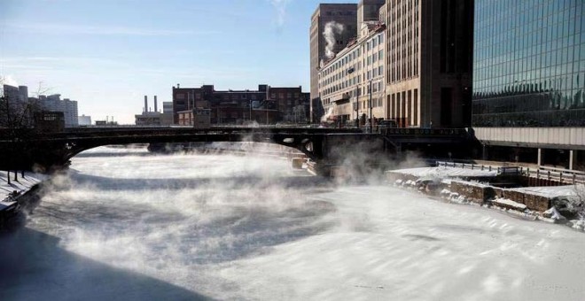 Varias personas cruzan un puente mientras la niebla se eleva desde el río Chicago. (KAMIL KRZACZYNSKI | EFE)