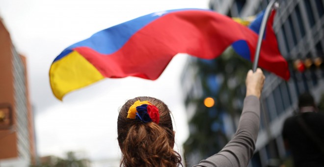Una mujer ondea una bandera de Venezuela durante una manifestación en contra de Nicolás Maduro. / REUTERS - ANDRES MARTINEZ CASARES