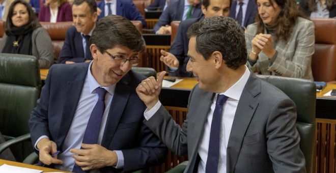 06/02/2019.- El presidente andaluz, Juanma Moreno, y el vicepresidente, Juan Marín (i), conversan en sus escaños durante el pleno del Parlamento de Andalucía esta tarde en Sevilla, que ha elegido, en la primera sesión plenaria de la XI Legislatura, a los