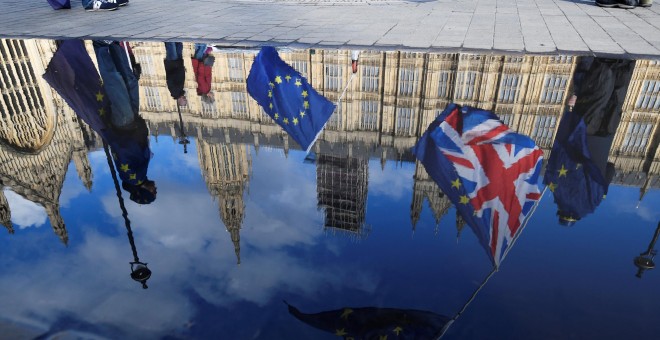 Banderas del Reino Unido y de la UE, reflejadas en un charco de agua frente al Parlamento británico, en Westminster, en una manifestación conraria al brexit. REUTERS/Toby Melville