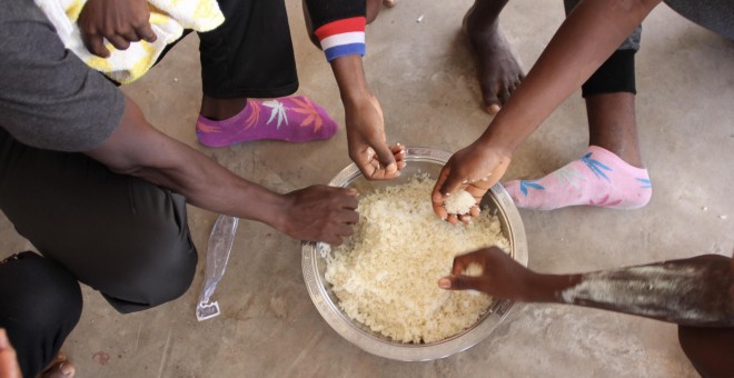 Un grupo de refugiados del campamento libio de Sbaa, compartiendo un cuenco de arroz — MSF