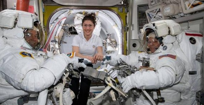 La astronauta de la NASA Christina Koch (centro) asiste a sus compañeros astronautas Nick Hague (izquierda) y Anne McClain (derechea) para ajustar sus trajes espaciales poco antes de comenzar su primer paseo espacial el pasado 22 de marzo. / NASA