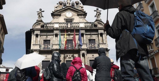 Un grupo de turistas se protegen con sus paraguas de la lluvia junto al Ayuntamiento de Pamplona, uno de los lugares preferidos para la Semana Santa. EFE