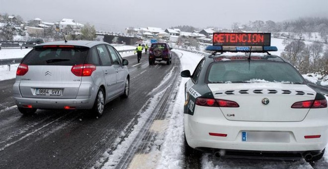 Efectivos de la Guardia Civil trabajan para descongestionar una retención por nieve en la autovía A-52, en Ourense. Las nevadas y las bajas temperaturas registradas en las últimas horas han provocado complicaciones desde primera hora de este sábado en la