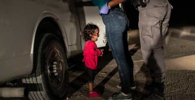 La niña Yana, de Honduras, llora mientras su madre, Sandra Sánchez, es cacheada por un policía estadounidense en la frontera en Texas./ JOHN MOORE (GETTY IMAGES)