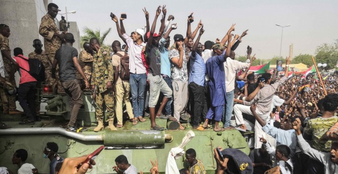 11/04/2019 - Los manifestantes sudaneses en pie sobre un vehículo militar blindado del ejército, tras el anuncio de renuncia de al-Bashir, 11 de abril de 2019 | AFP