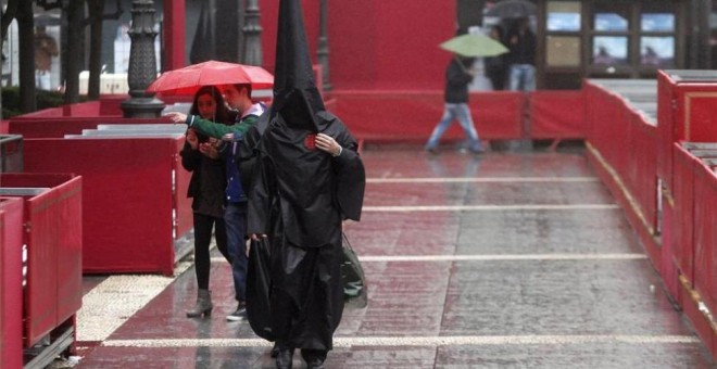 Imagen de archivo de un nazareno del Sepulcro que camina bajo la lluvia. SALAS / EFE