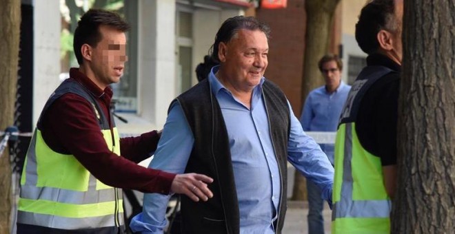 El presidente del Huesca, Agustín Lasaosa,d., junto a un policia a su salida de las oficinas del club tras ser detenido. /EFE