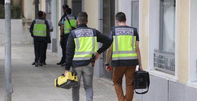 Agentes de la Policía trabajan ante la vivienda de Xàtiva donde la mujer fue asesinada. EFE/Natxo Francés