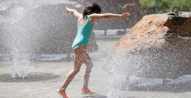 En la imagen, una niña juega en una fuente buscando refrescarse tras las altas temperaturas | EFE