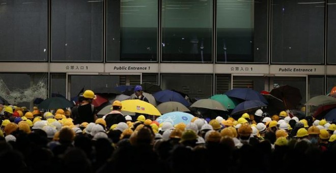 01/07/2019.- Un grupo de manifestantes permanecen congregados a las puertas del Consejo Legislativo en Hong Kong (China) este lunes. Decenas de manifestantes trataron de irrumpir hoy en la sede del Consejo Legislativo de Hong Kong rompiendo cristales y pu