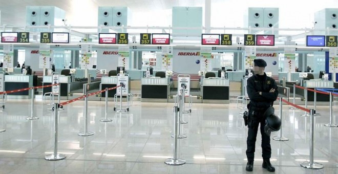 Un mosso de esquadra ante los mostradores de facturación de Iberia, en el aeropuerto de Barcelona-El Prat. EFE/Andreu Dalmau/Archivo