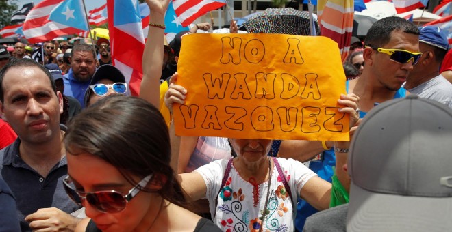 Una mujer sostiene una pancarta durante las protestas en San Juan / REUTERS