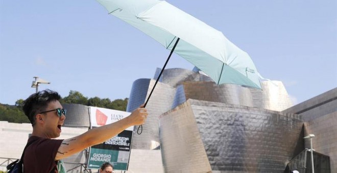 Un turista se protege del sol ante el museo Guggenheim de Bilbao, uno de los destinos demandados en vacaciones. /EFE