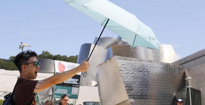 Un turista se protege del sol ante el museo Guggenheim de Bilbao, uno de los destinos demandados en vacaciones. /EFE