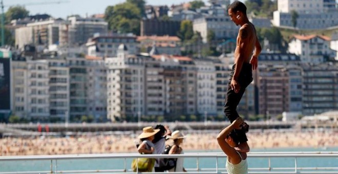 Unos jóvenes practican acrobacias junto a la playa de la Concha de San Sebastián / EFE - JUAN HERRERO