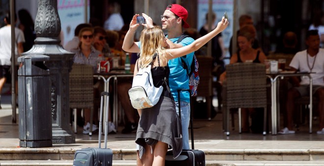Varios turistas toman fotografías con sus teléfonos móviles por el centro de la ciudad de València. EFE/Ana Escobar