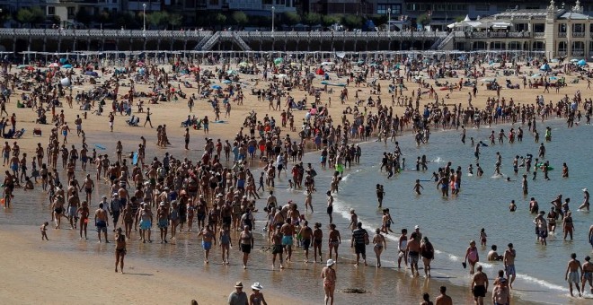 14/08/2019.- Donostiarras y visitantes pasean por la playa de La Concha de San Sebastián. / EFE - JAVIER ETXEZARRETA