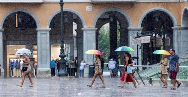 Varias personas se protegen con paraguas de la lluvia en la Plaza Mayor de Palma de Mallorca. /EFE