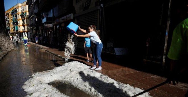 hoy27/08/2019.- Una ciudadana vacía un cubo de granizo en la calle después de la tormenta y la granizada que cayó este lunes en Arganda del Rey (Madrid) causando importantes daños materiales. EFE/ David Fernández