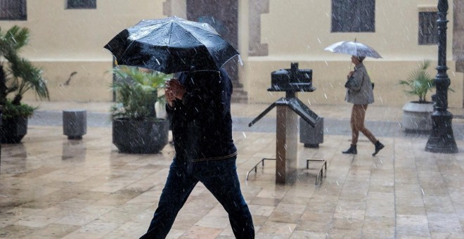 Una persona se protege de la lluvia con un paraguas, esta mañana en València./EFE