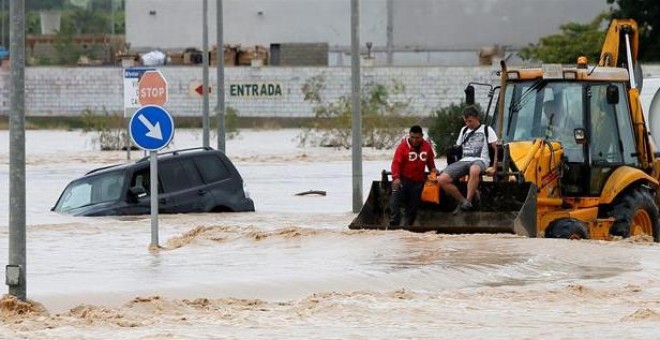 Dos ocupantes de un vehículo son rescatados con una pala mecánica, mientras la carretera permanece inundada por el efecto de las riadas, este viernes, en la ciudad alicantina de Orihuela, que se encuentra incomunicada, a causa del desbordamiento del río