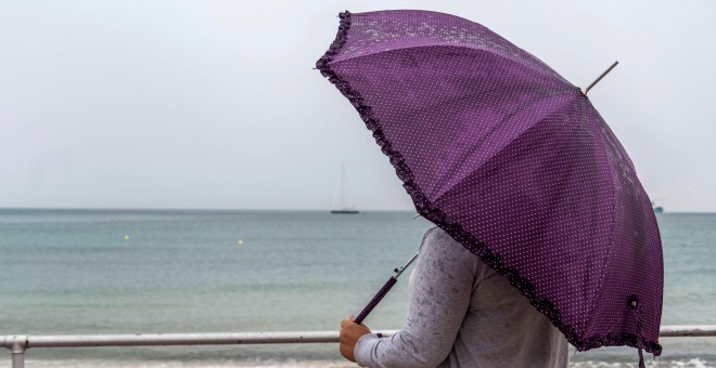 Una mujer se protege de la lluvia este viernes en Palma de Mallorca. EFE/Cati Cladera