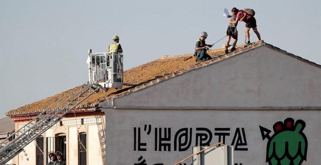 27/09/2019 - Los dos jóvenes que se han encaramado al tejado de la alquería Forn Barraca, en el término de Alboraia, para impedir su derribo, se abrazan antes de ser detenidos por la Guardia Civil. EFE/Manuel Bruque