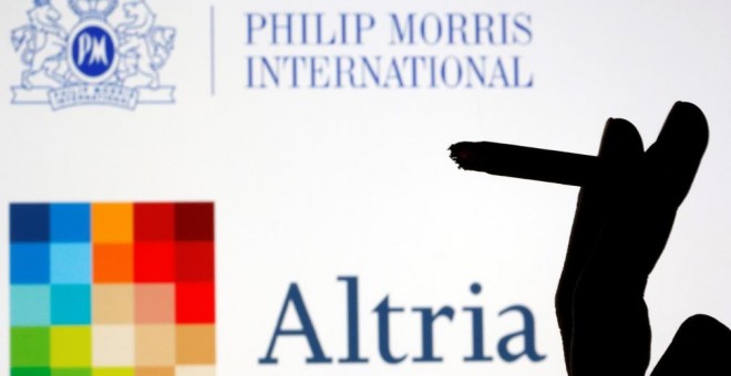 Unos dedos sujetan un cigarrillo en una composición con los logos de Altria y de Philip Morris. REUTERS