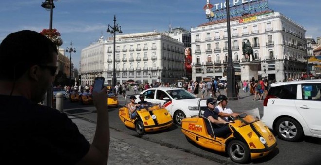 Un hombre toma fotos de turistas en una visita autoguiada de Gocar en la Plaza Puerta del Sol de Madrid. REUTERS/Susana Vera