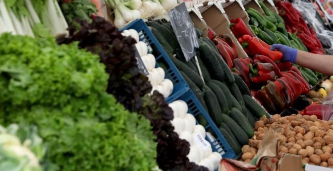 Un vendedor recoge un pimiento rojo en una verdulería en un mercado de Madrid. REUTERS/Sergio Pérez